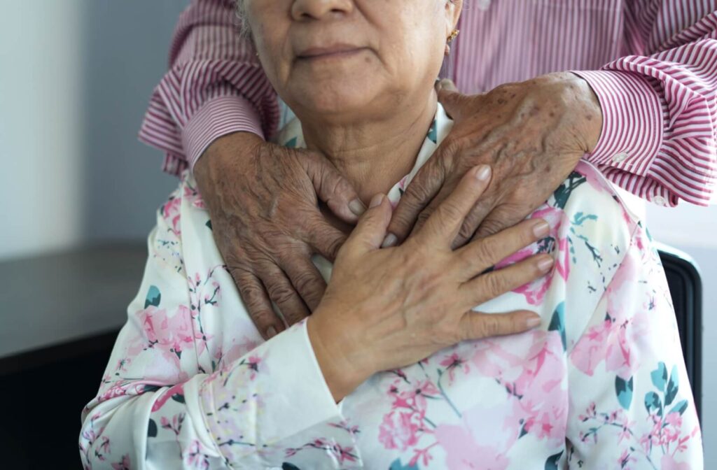 Older person dining at a restaurant table smiling at their companion while enjoying a fresh salad and glass of white wine